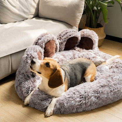 Grey paw-shaped Dogegis™ calming dog bed placed in a modern living room setting.